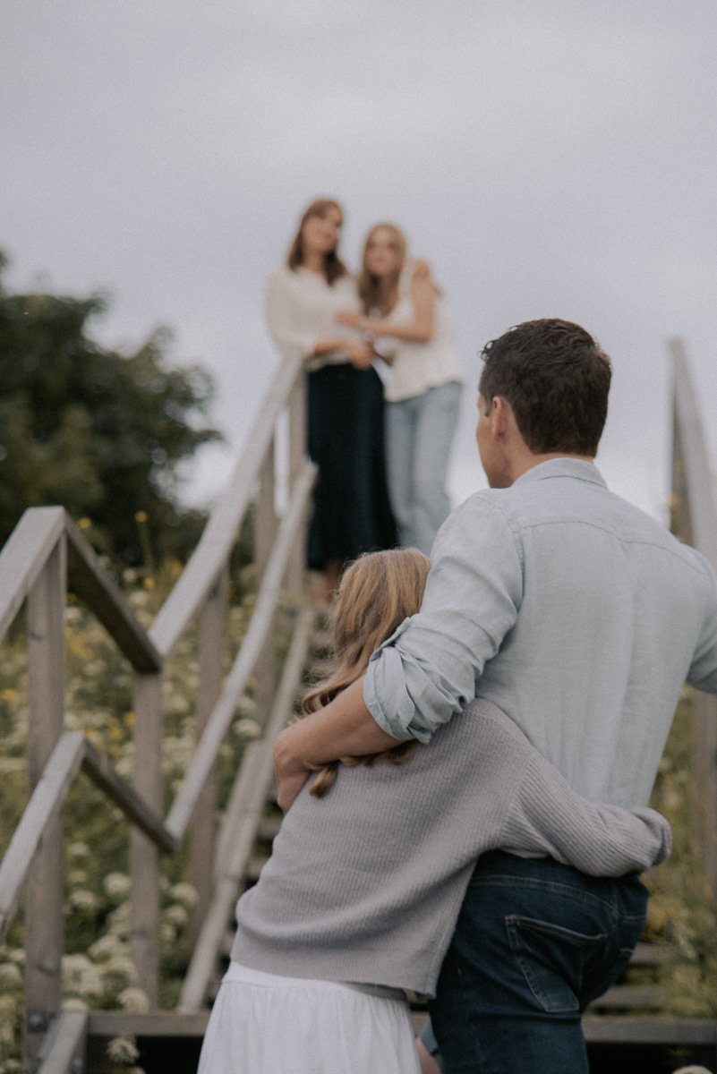 Perhekuva, jossa etualalla isä ja tytär halaavat toisiaan ja taustalla näkyy taustalla äiti ja toinen tytär.