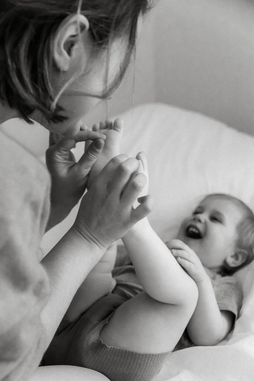 Äiti ja iloinen lapsi mustavalkoisessa kuvassa. Kuvannut valokuvaaja Heidi Väisänen.