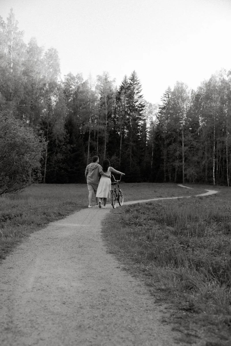 Mustavalkoinen kuva, jossa pariskunta taluttaa pyörää. Pariskuntakuvaus Lauttasaari.