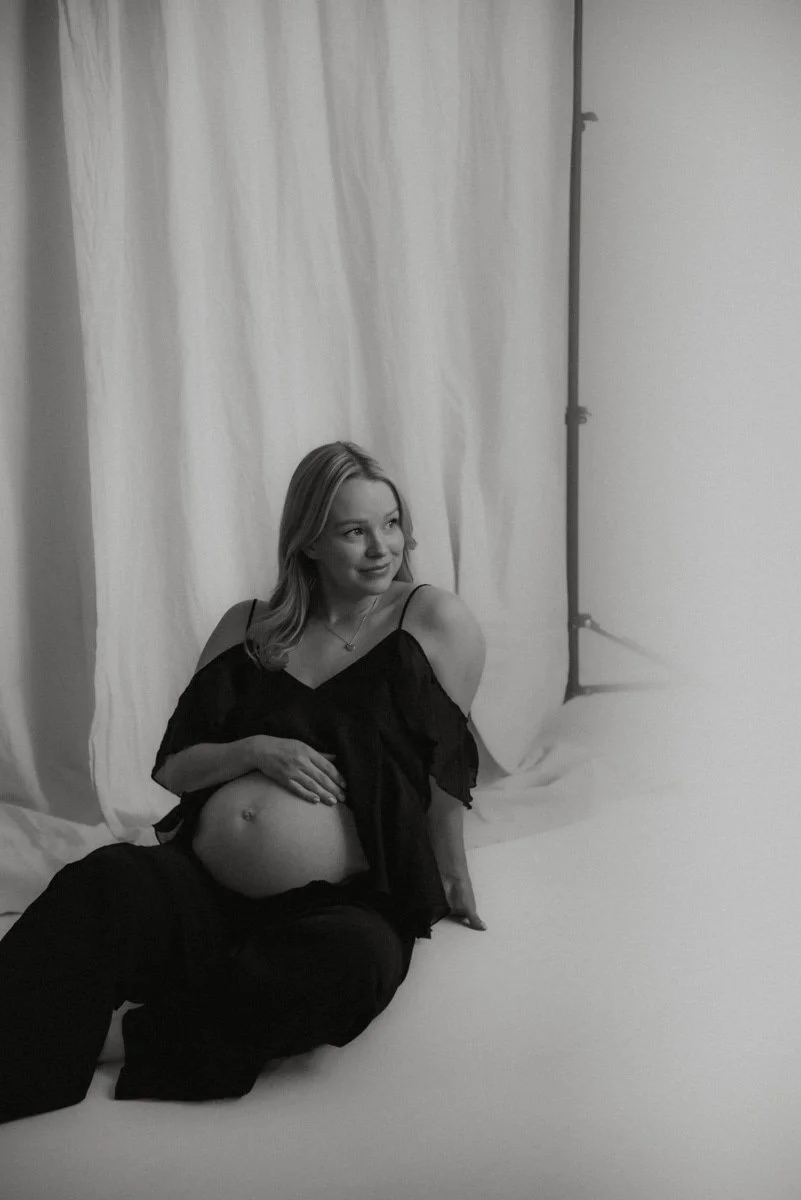 Odottava äiti istuu kuvattavana studion lattialla.