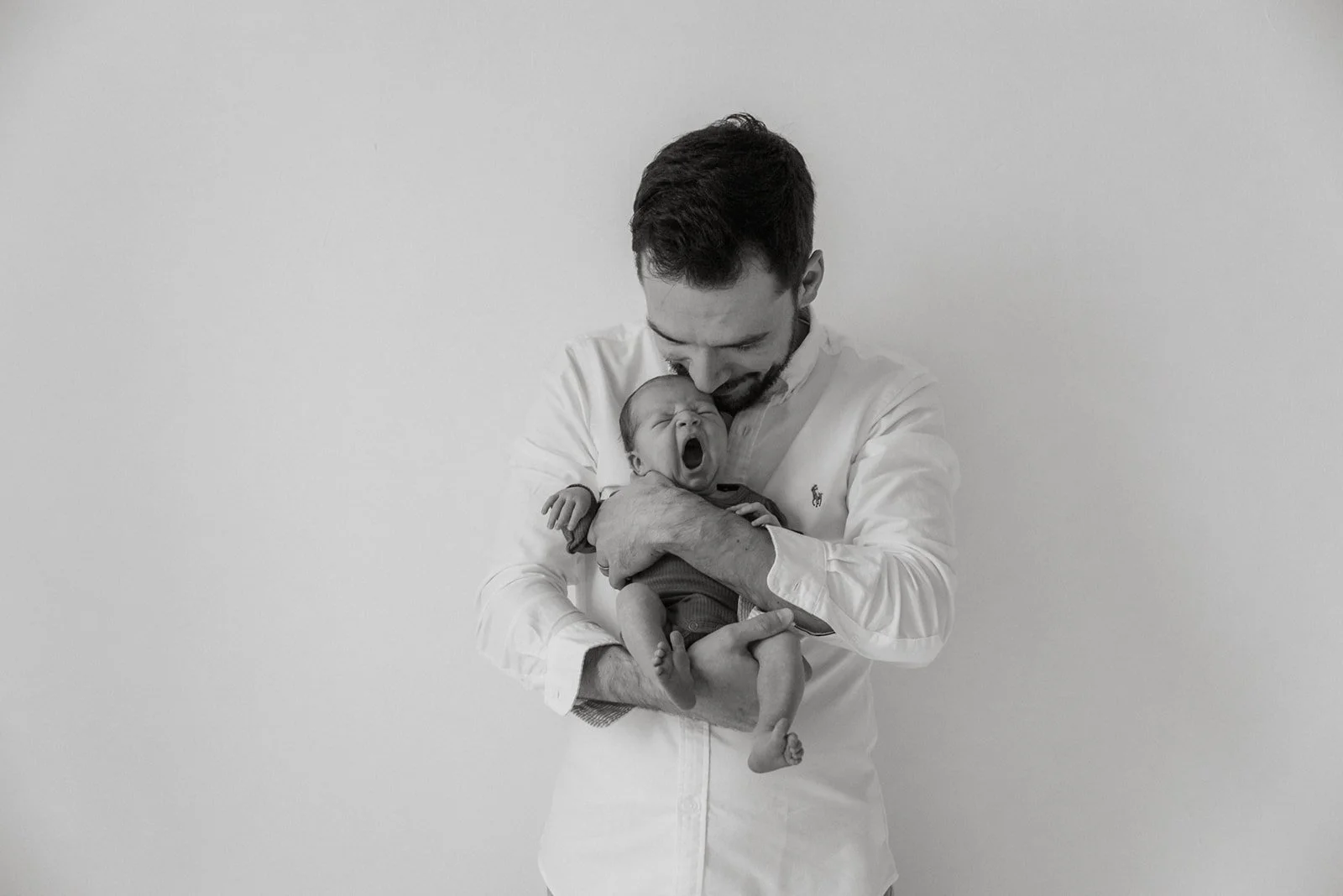 Pieni vastasyntynyt vauva isän hellässä syleilyssä. Kuvan on ottanut vauvakuvaaja Heidi Väisänen.