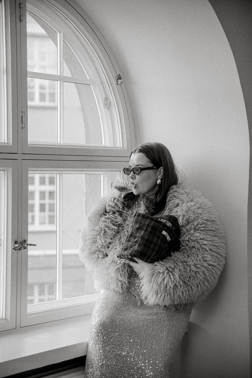 Muotokuva naisyrittäjästä ikkunan edessä. Edlan brändikuvaus, yrittäjällä brändin laukku kädessään.