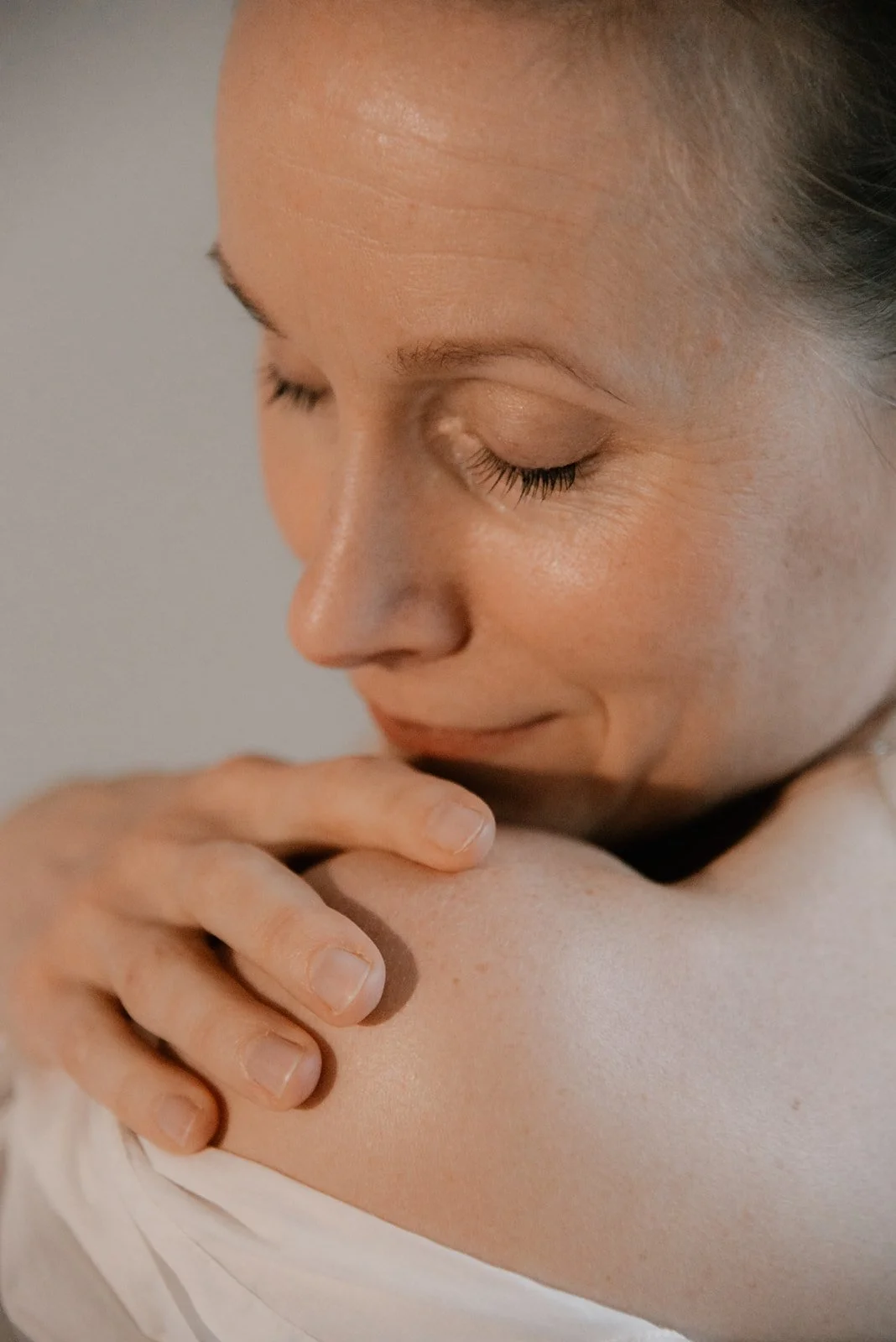 Lähikuva naisen olkapäästä ja kasvoista.