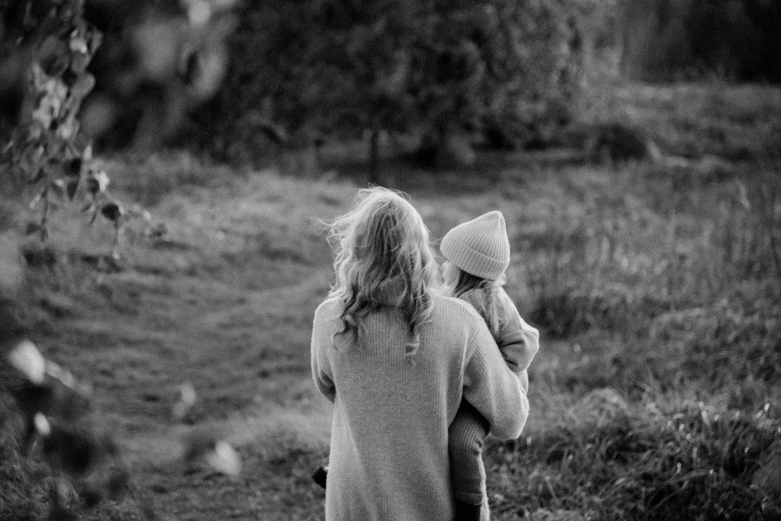 Perhekuvaus luontomiljöössä, äiti kantaa pientä lasta sylissään. Kuvannut valokuvaaja Heidi Väisänen.