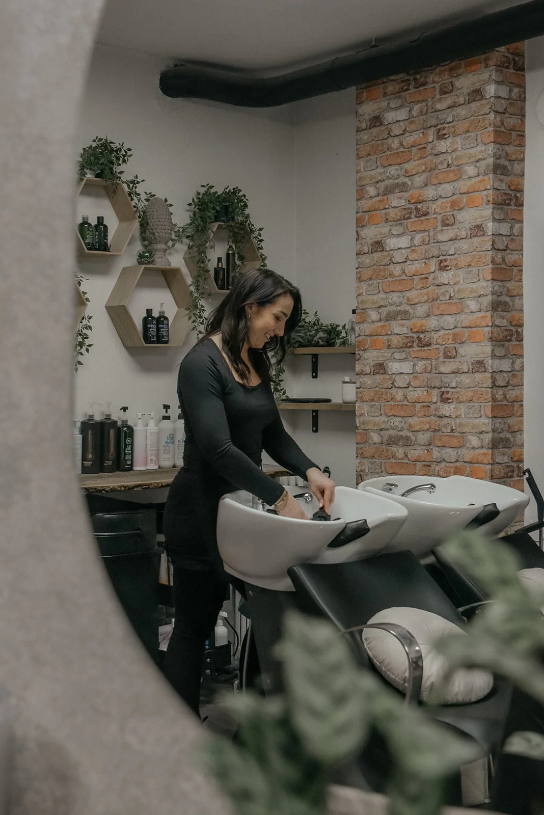 Heidi Väisäsen toteuttamat Hykken brändikuvat. Kampaaja seisoo pesupisteellä.