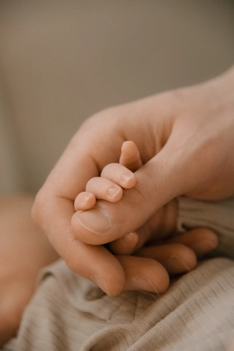 Isä pitelee vauvan pieniä sormia käsissään. Vauvakuvaus Helsinki.