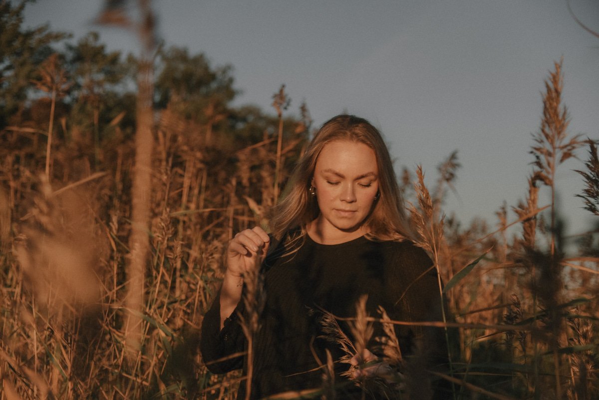 Ilta-auringossa kylpevä hehkuva odottava äiti. Odotusajankuvaus Espoo.