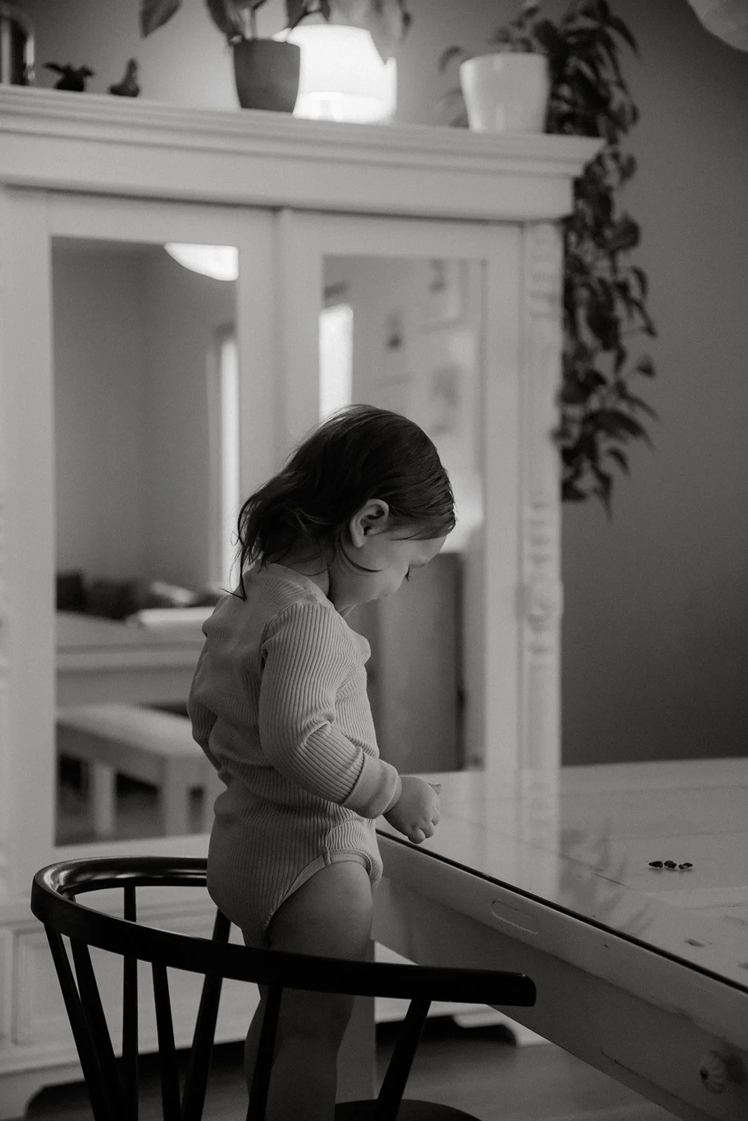 Lapsi leikkii tuolilla kuvauksessa. Perhekuvaus kotona. 