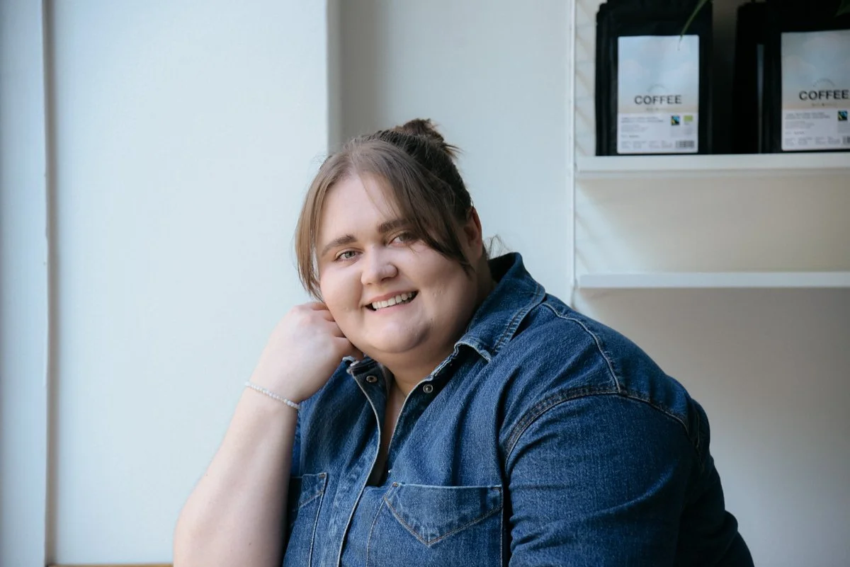 Iloinen Bakerikan naisyrittäjä poseeraa henkilökuvassa kameralle ikkunan edessä.