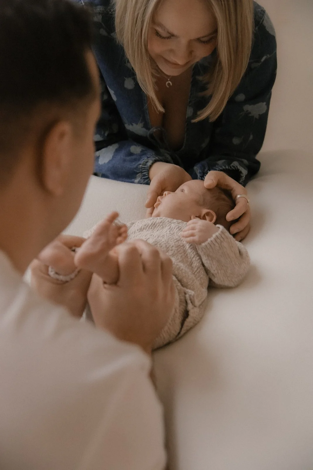 Vauvavuoden kuvaus, isä ja äiti pitelevät yhdessä vauvaa sängyn päällä.