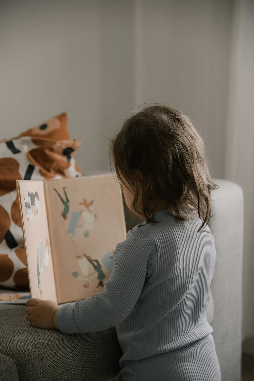Lapsi lukee leppoistasi kirjaa. Kuvan on ottanut lapsikuvaaja Heidi Väisänen.