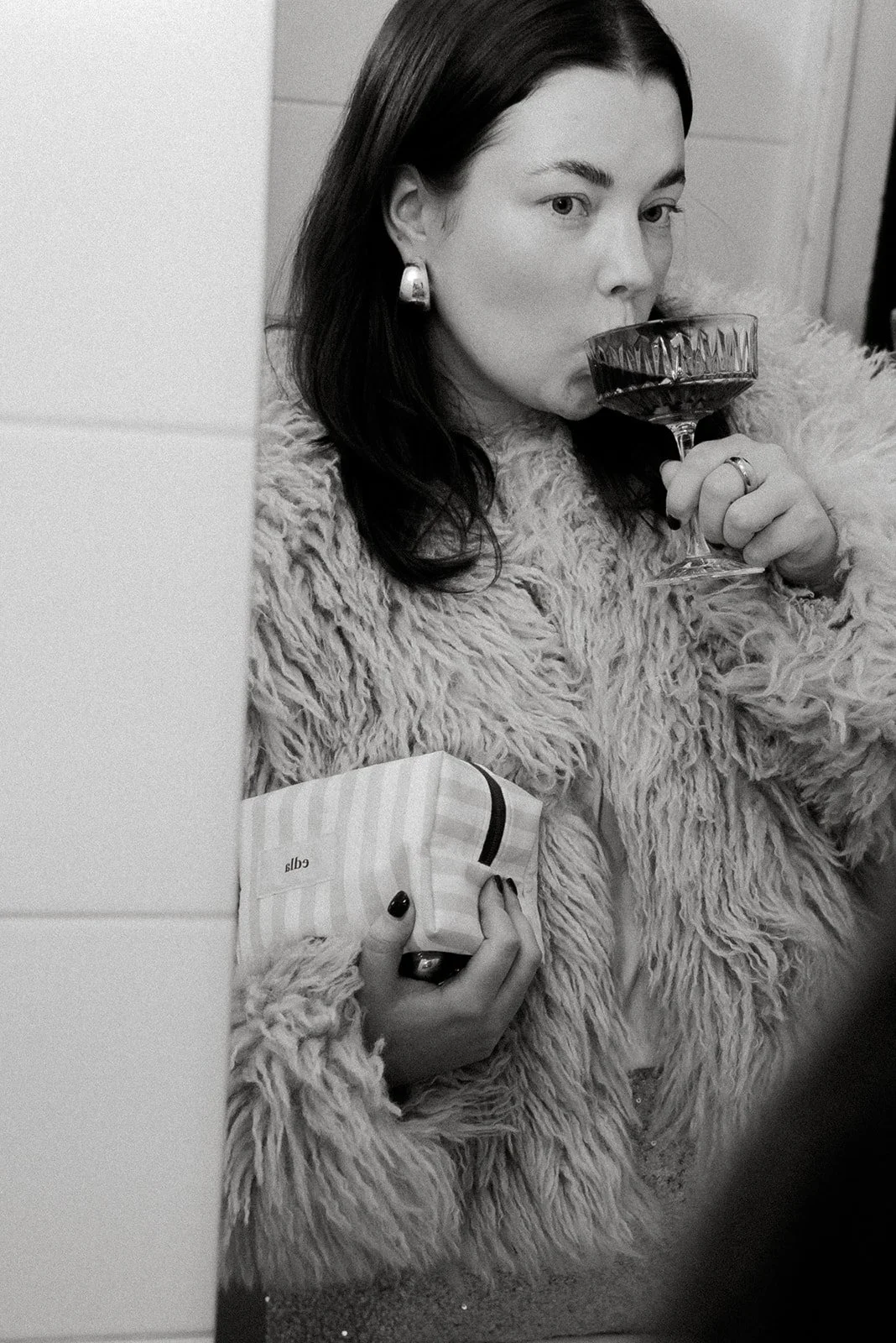 Edlan brändikuvaus, yrittäjä siemailee drinkkiä brändin meikkipussi kainalossaan.