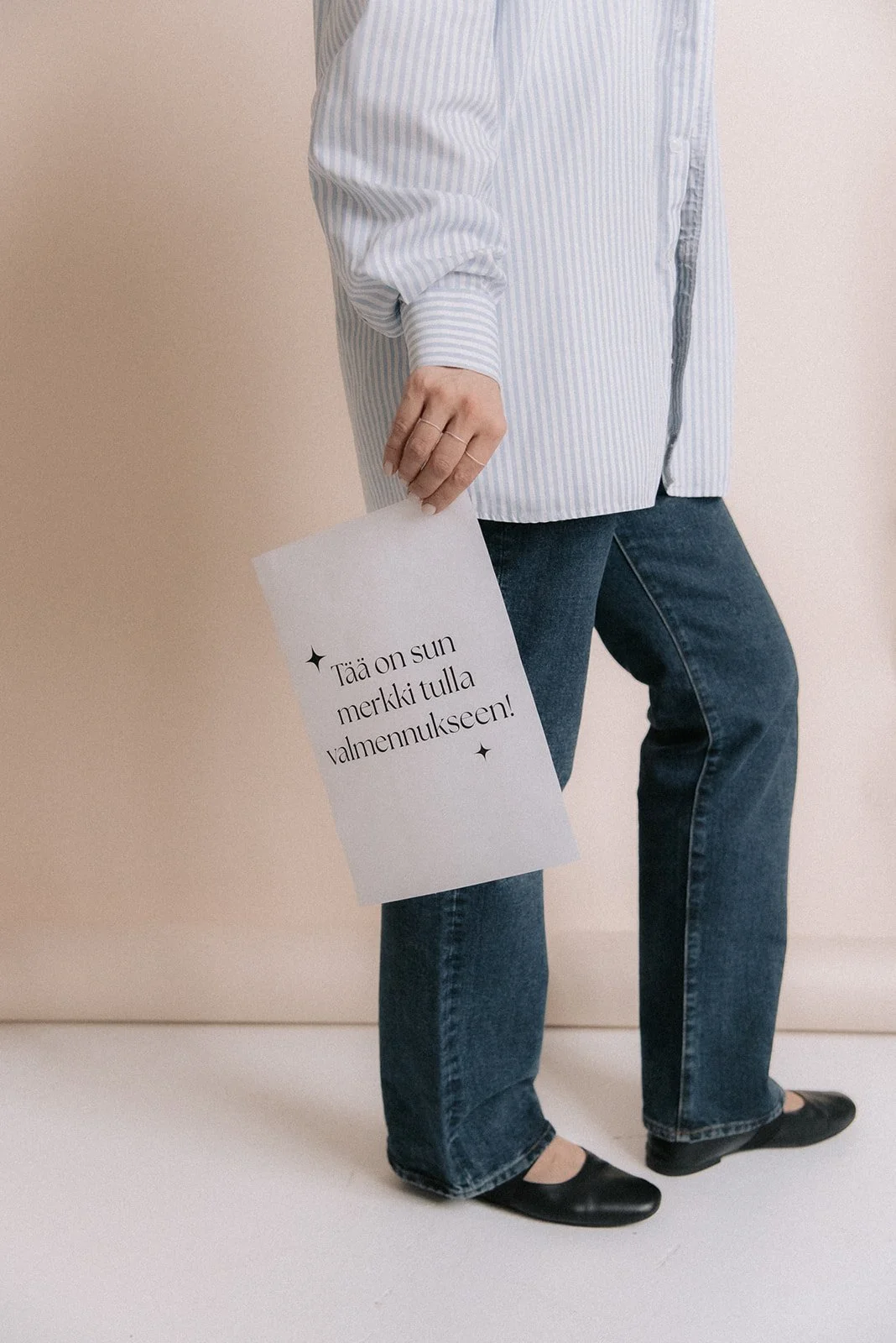 Yrityskuvaus harmonisessa studiossa. Heartiven yrittäjä pitelee kädessään lappua, jossa lukee "Tämä on sun merkki tulla valmennukseen".