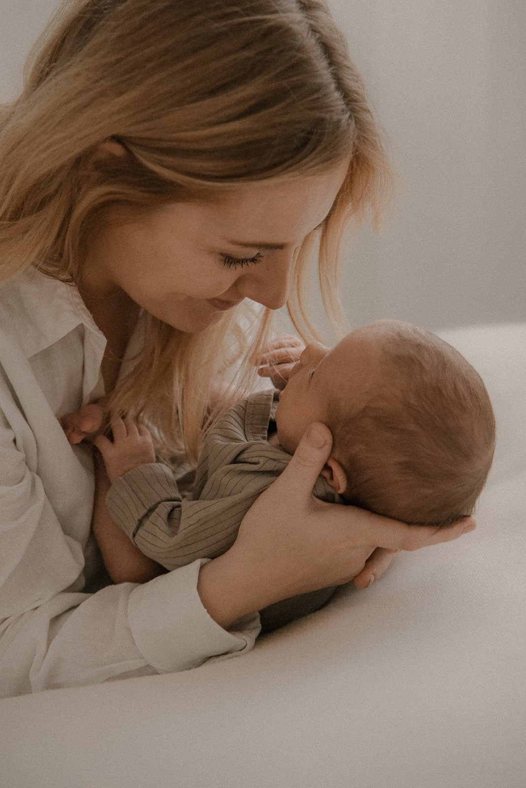 Vauvakuvaus, äiti pitelee vauvaa hellästi kasvojensa lähellä.