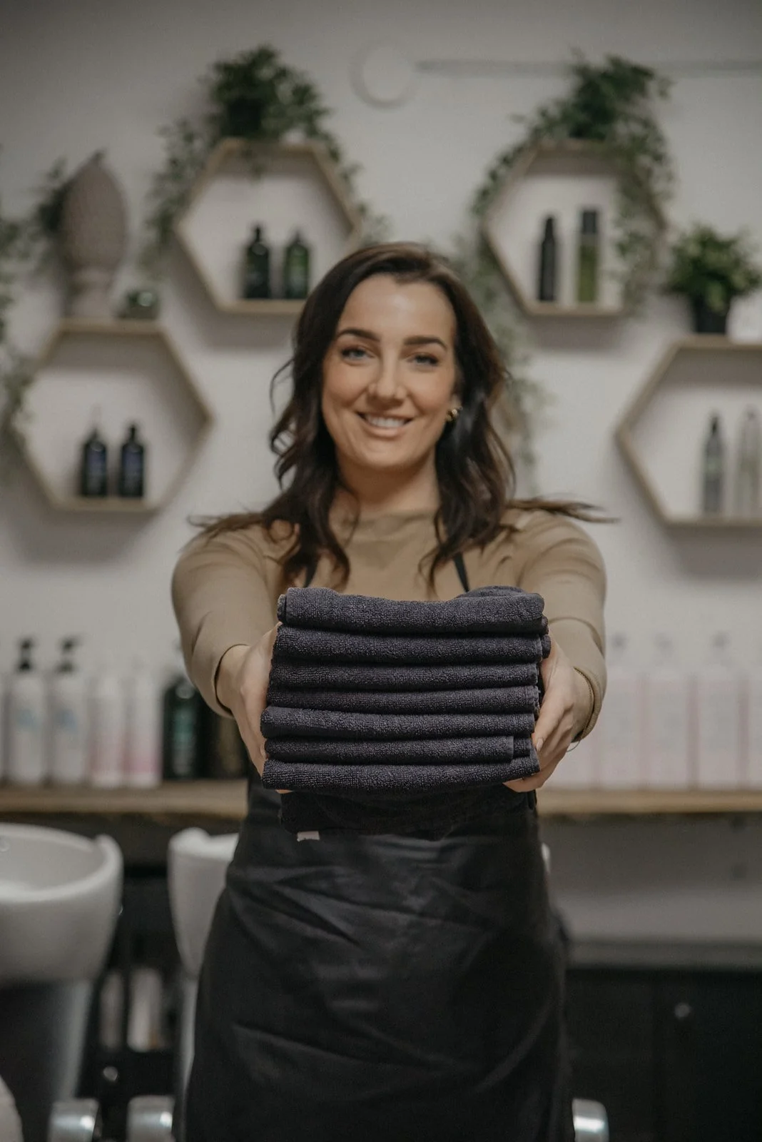 Hykken brändikuvaus, naisyrittäjä hymyilee ja pitelee käsissään kasaa pyyhkeitä.