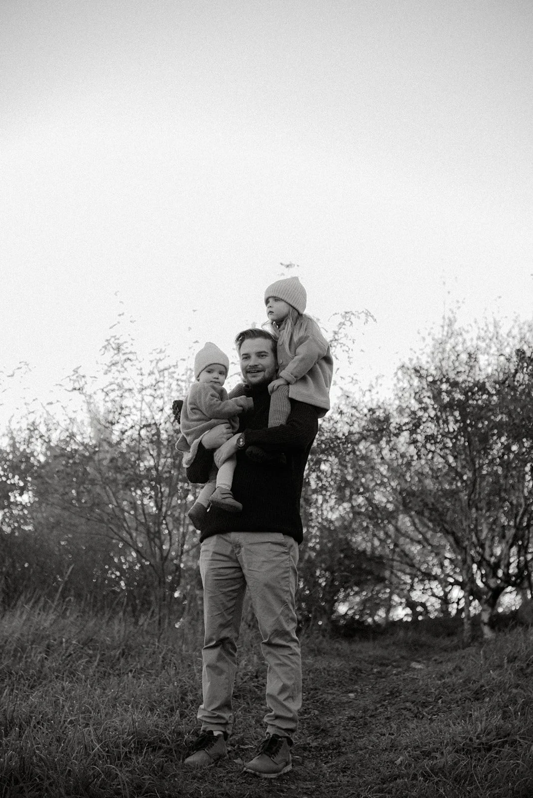 Mustavalkoinen perhekuva isästä ja kahdesta lapsesta.