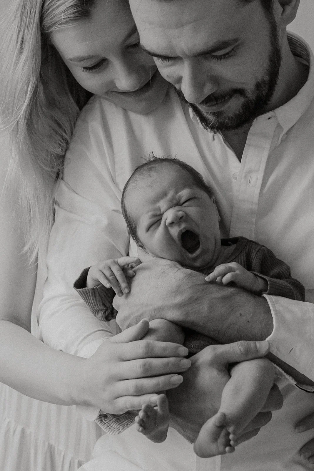 Haukotteleva vastasyntynyt vanhempien sylissä. Vauvakuvaus pääkaupunkiseutu.