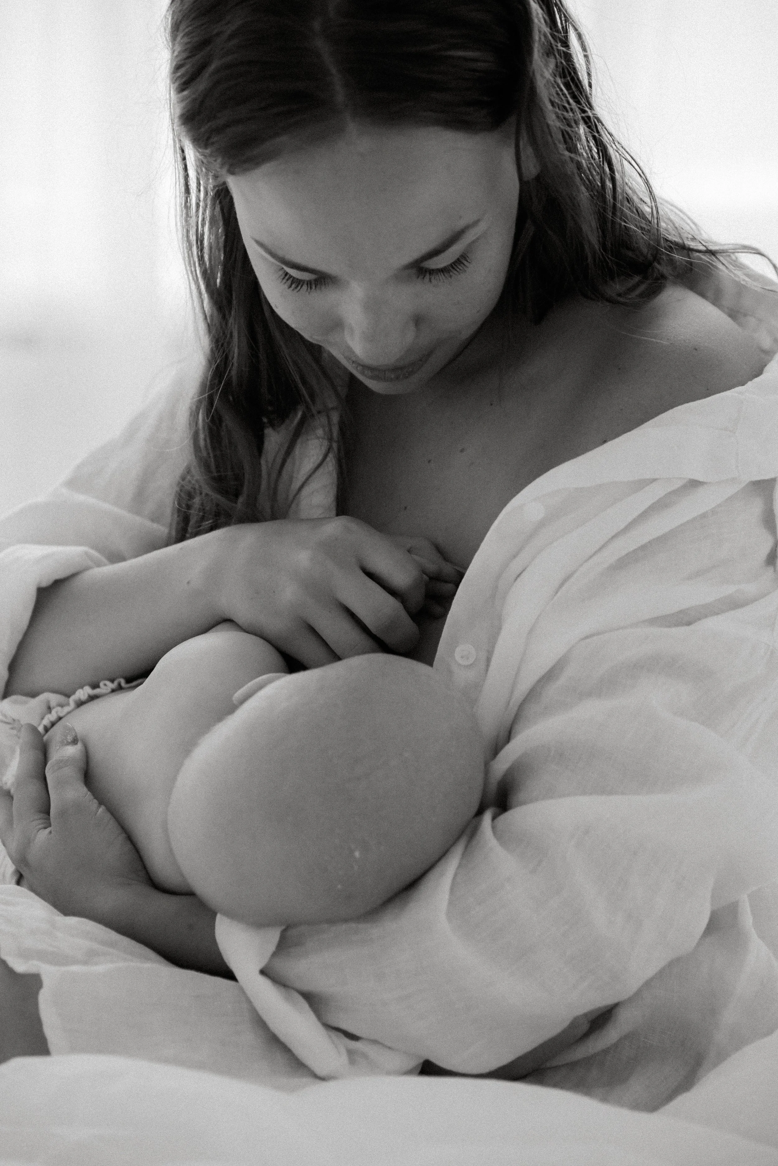 Mustavalkokuva, jossa vauva ja imettävä äiti. Äiti- ja vauvakuvaus Heidi Väisäsen studiolla.