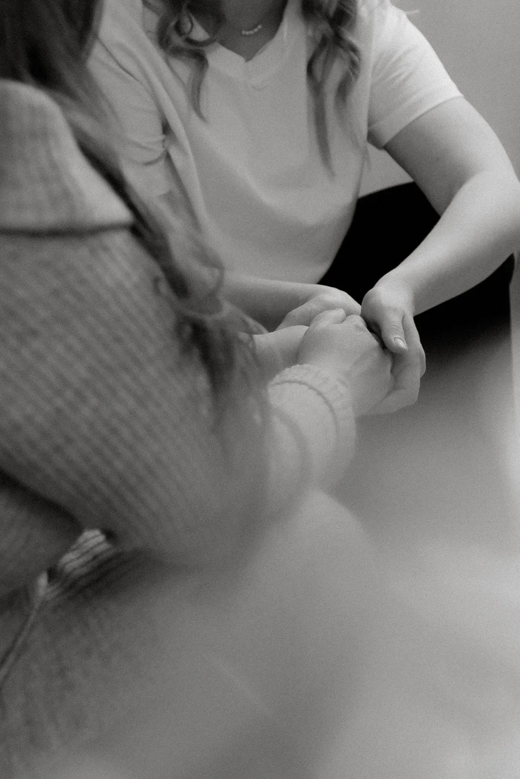 Mustavalkoinen tunnelmallinen brändikuva, doula pitelee asiakastaan kädestä kiinni.