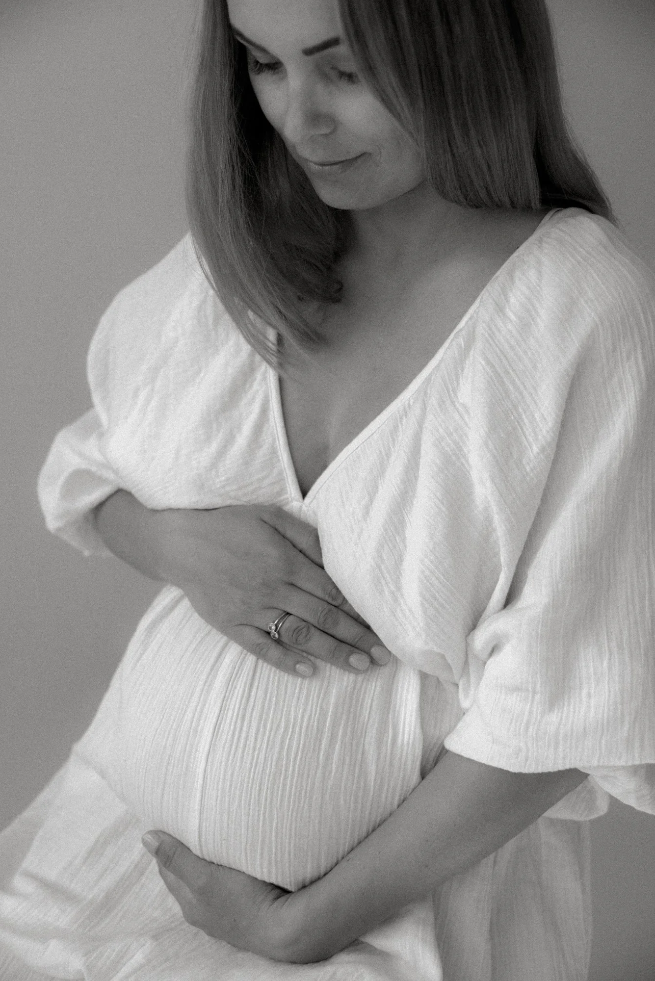 Mustavalkoisessa odotusajankuvassa äiti pitelee vatsaansa.