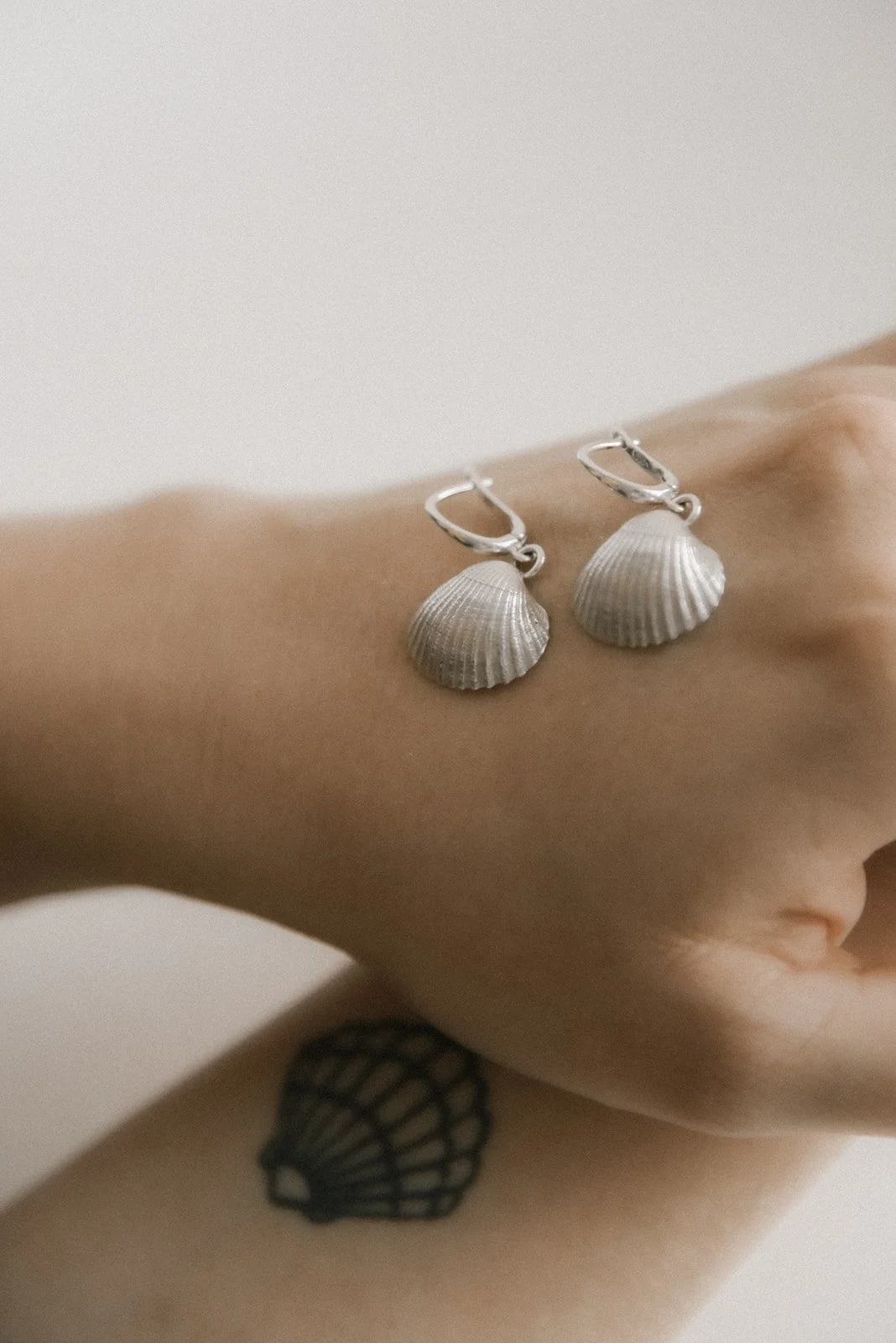 Tuotekuvaus, hopeiset korvakorut yrittäjän käsivarsilla.