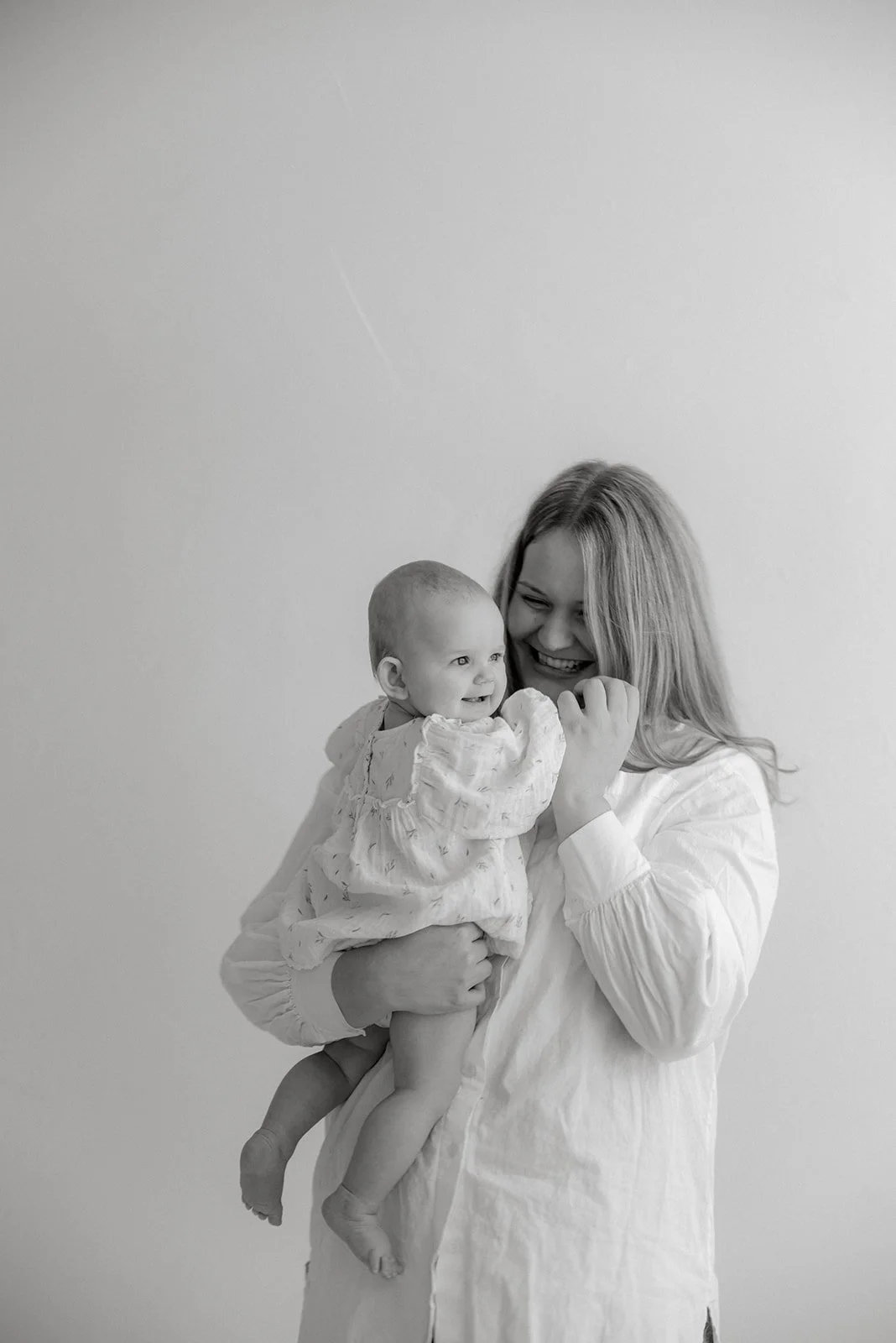 Äidin lämmin syli mustavalkokuvassa. Äiti- ja lapsikuvaus Heidi Väisäsen studiolla.