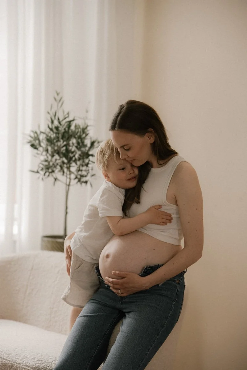 Lapsi halaa raskaana olevaa äitiä. Odotusajankuvaus Heidi Väisänen studiolla.
