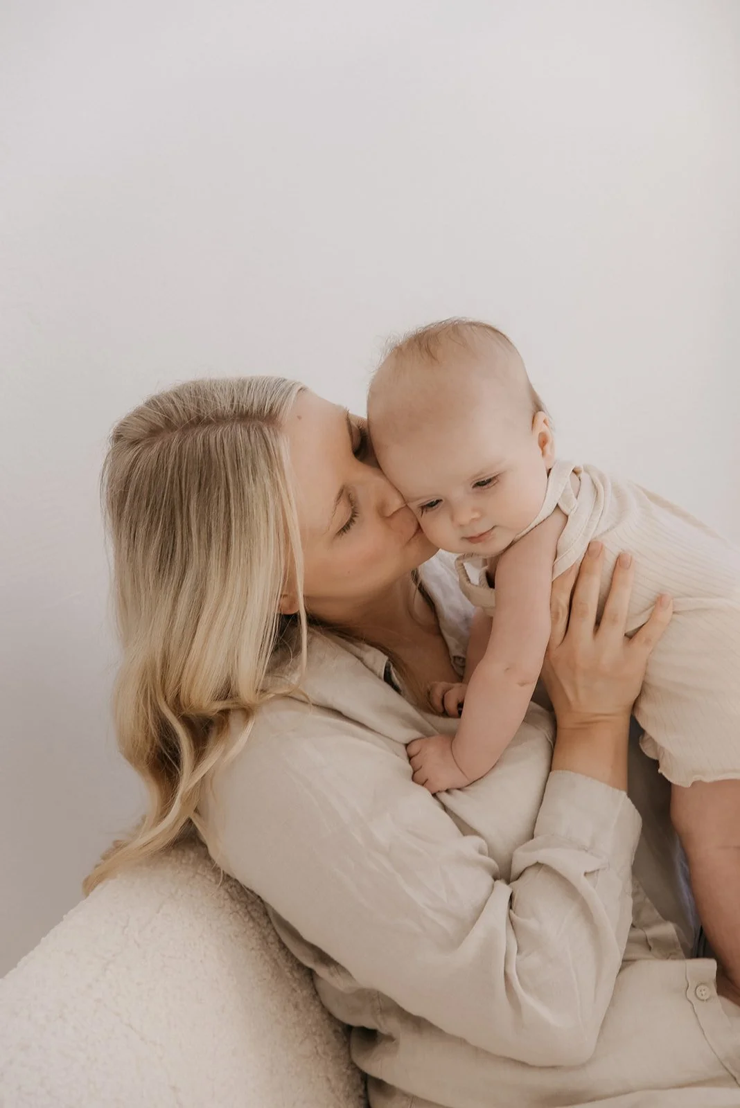 Äiti suukottaa hellästä vauvaa poskelle.