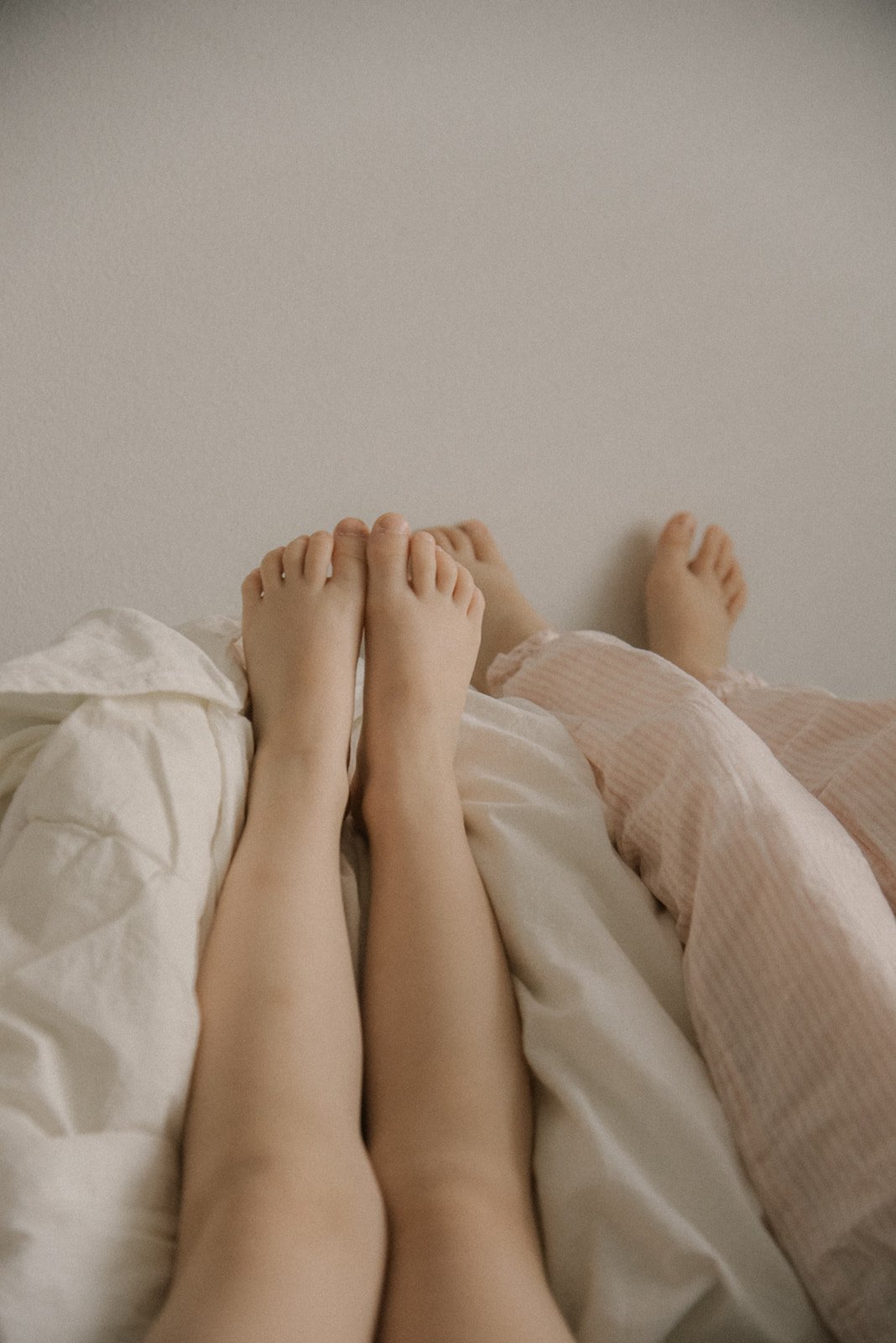 Vaaleassa kuvassa lasten jalkoja. Sisarkuvaus kotona.