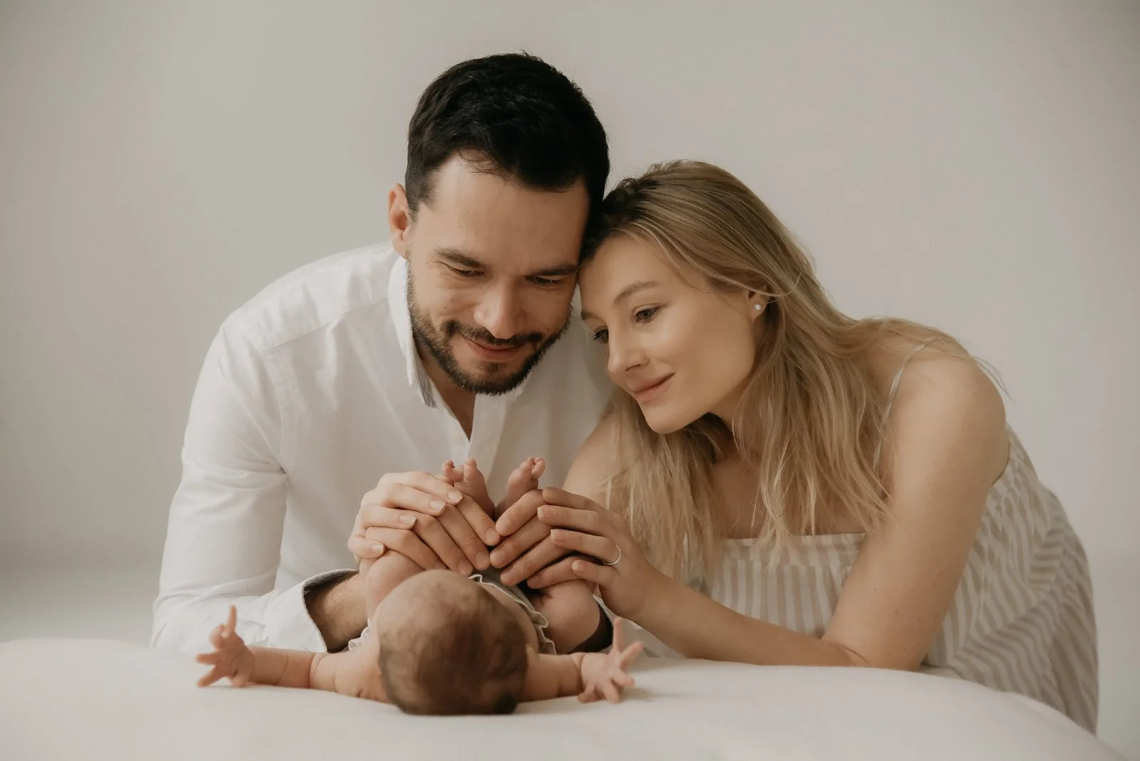 Perheen yhteiset ensi hetket, vanhemmat ja vauva kuvauksessa studiolla.