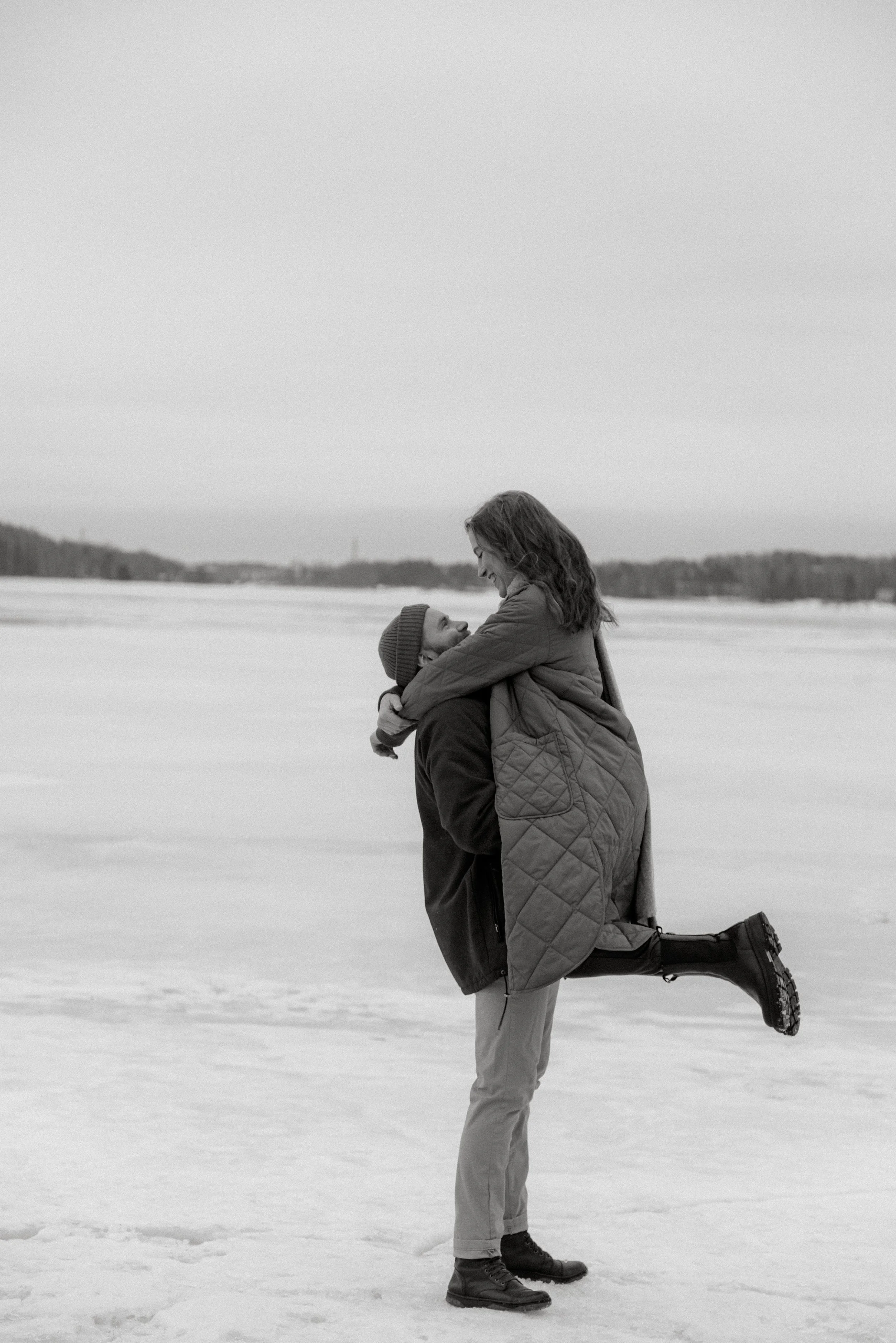 Nainen hyppää miehen syliin järven jäällä. Pariskuntakuvaus Espoo.