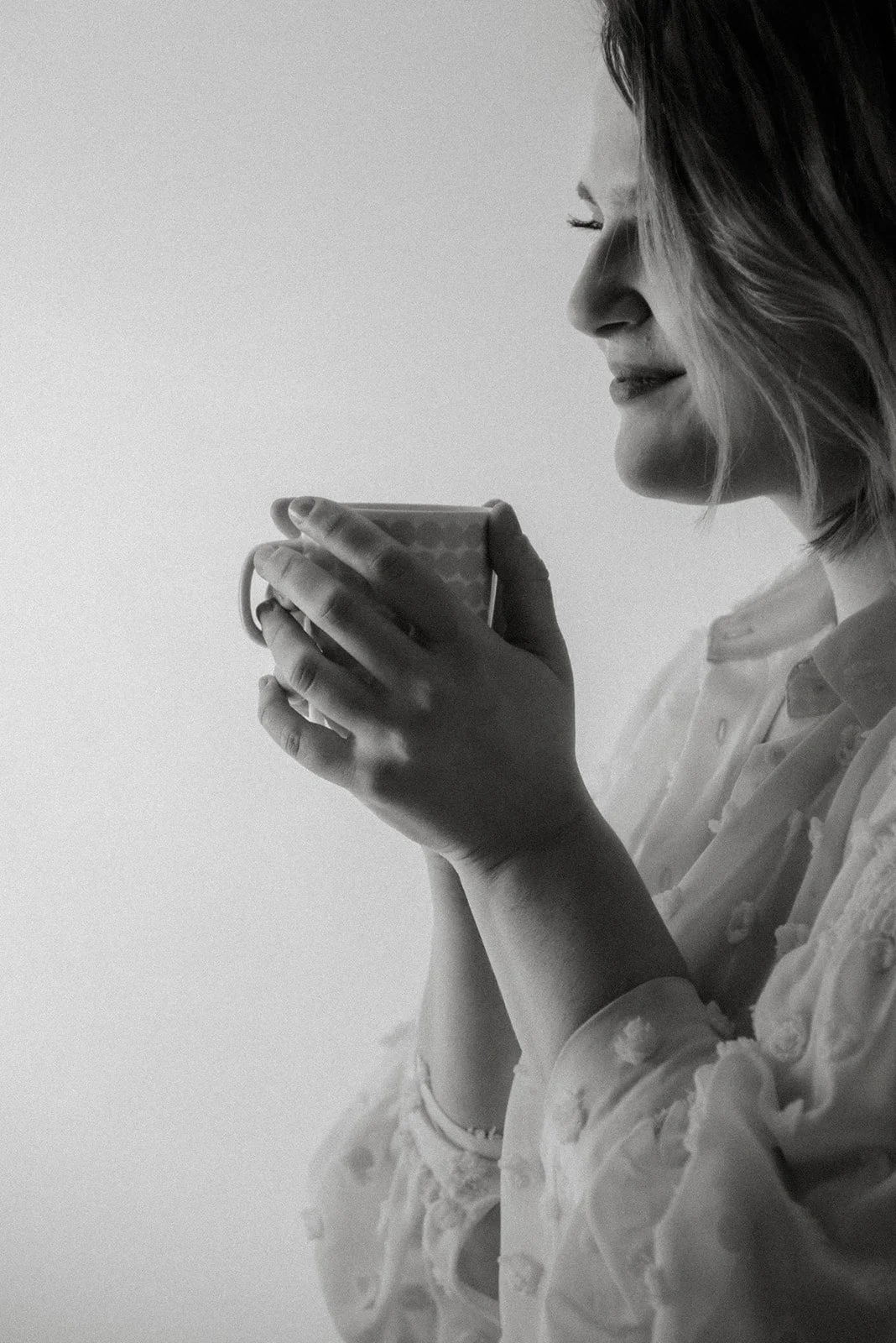 Äidin käsissä lämmin kuppi kahvia. Perhekuvaus kotona.