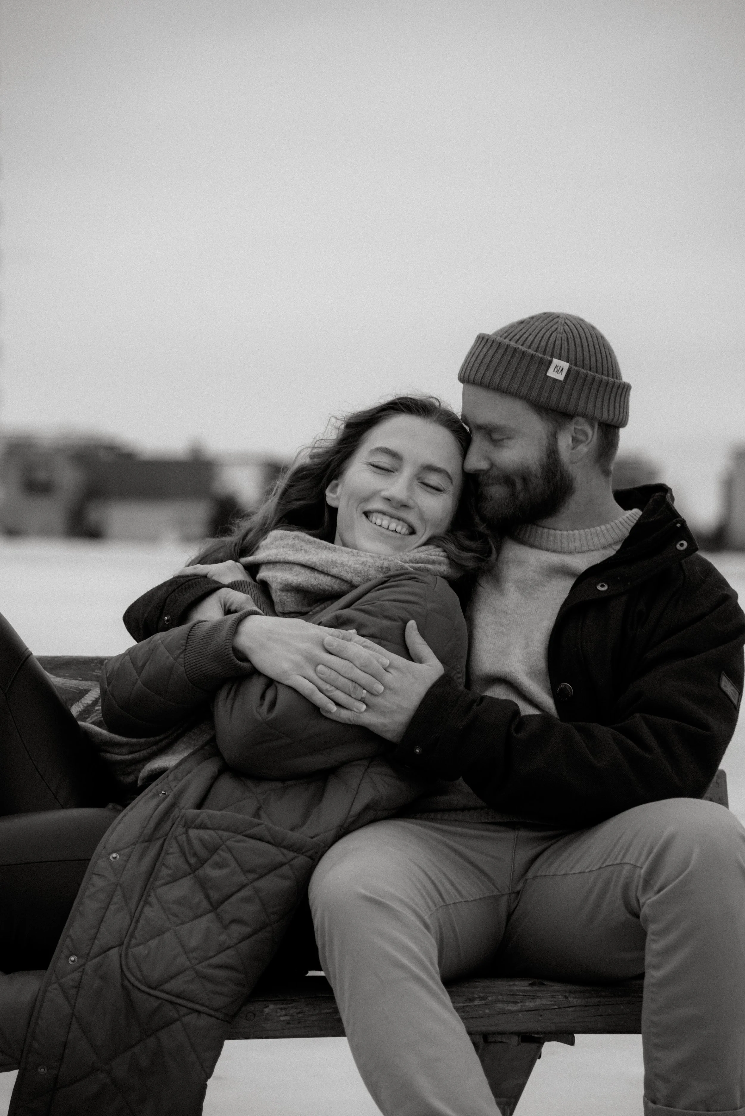 Pariskunta syleilee toisiaan puiston penkillä. Pariskuntakuvaus Espoo.