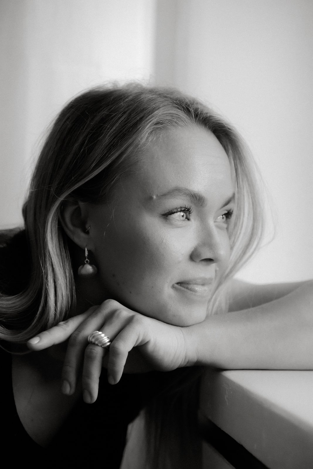 Mustavalkoinen henkilökuva. Naisyrittäjä katsoo ulos valoisasta ikkunasta.