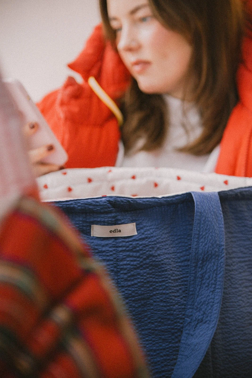 Tuotekuva Edlan laukusta, taustalla yrittäjä katsoo puhelintaan.