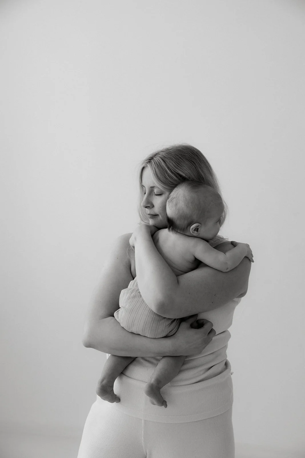 Äiti ja lapsi kuvattavana valoa tulvivassa studiossa.