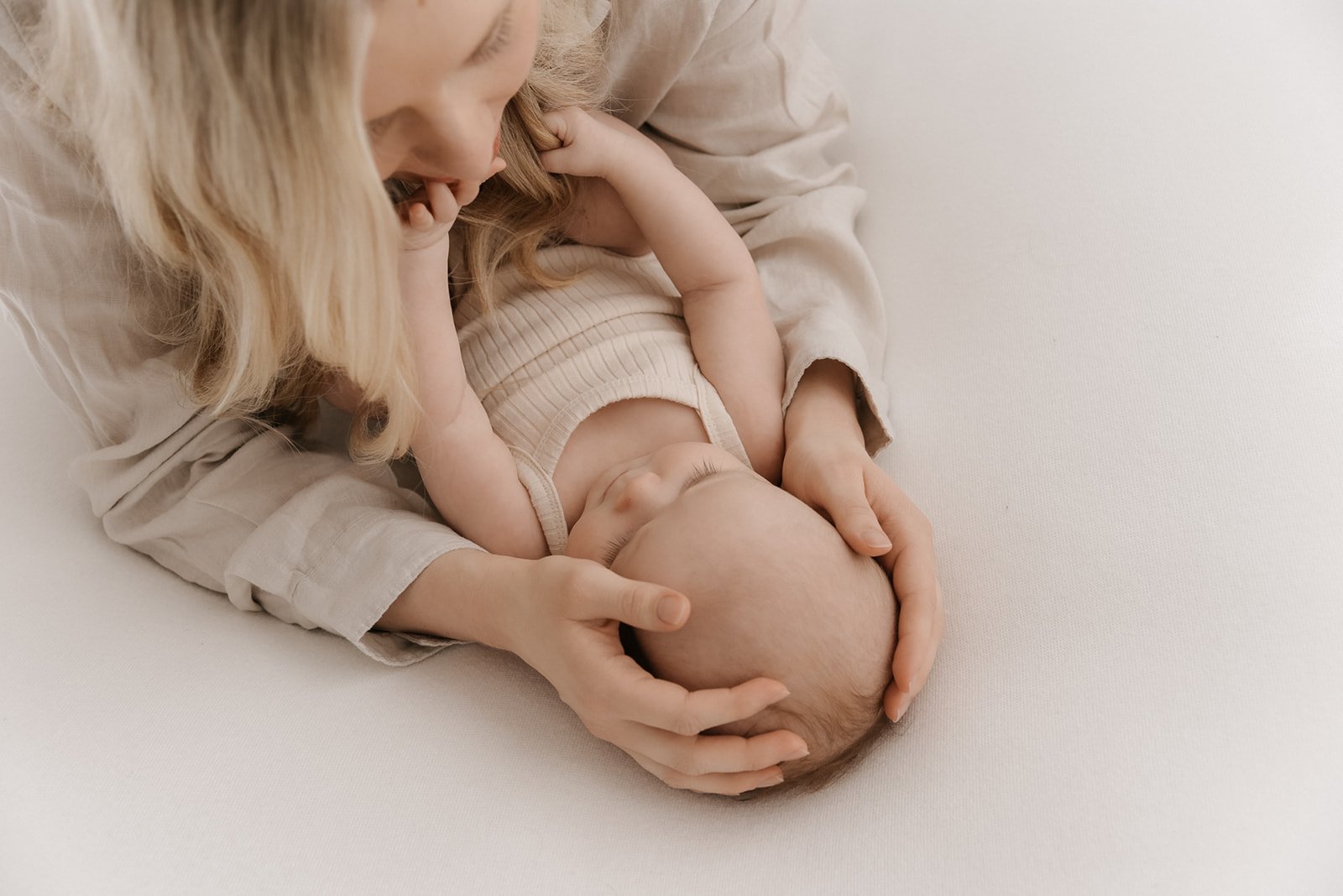 Äiti pitelee lapsensa päätä harmonisessa kuvassa. Äiti- ja vauvakuvaus studiossa.