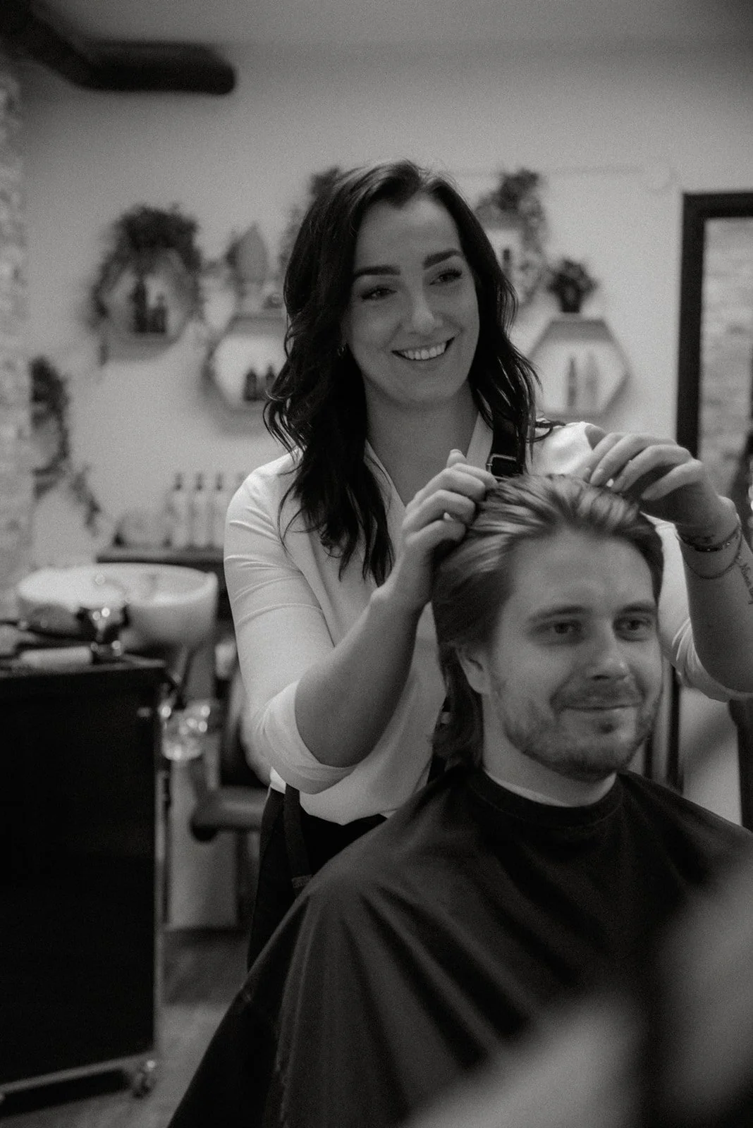 Kampaamon arkea brändikuvassa. Kampaajaa laittaa asiakkaan hiuksia.