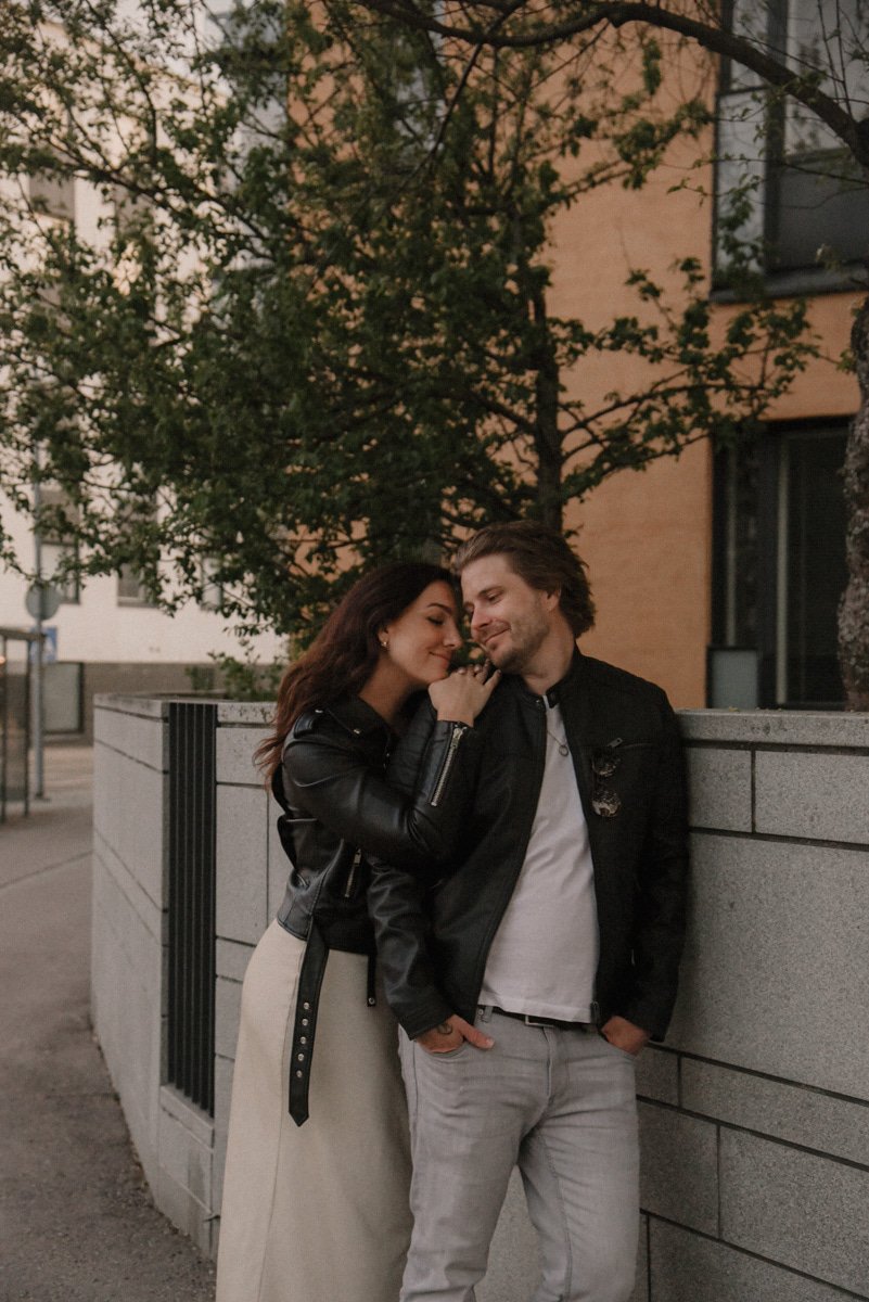 Pariskunta nojailee toisiinsa kaupunkimiljöössä. Pariskuntakuvaus Helsinki.