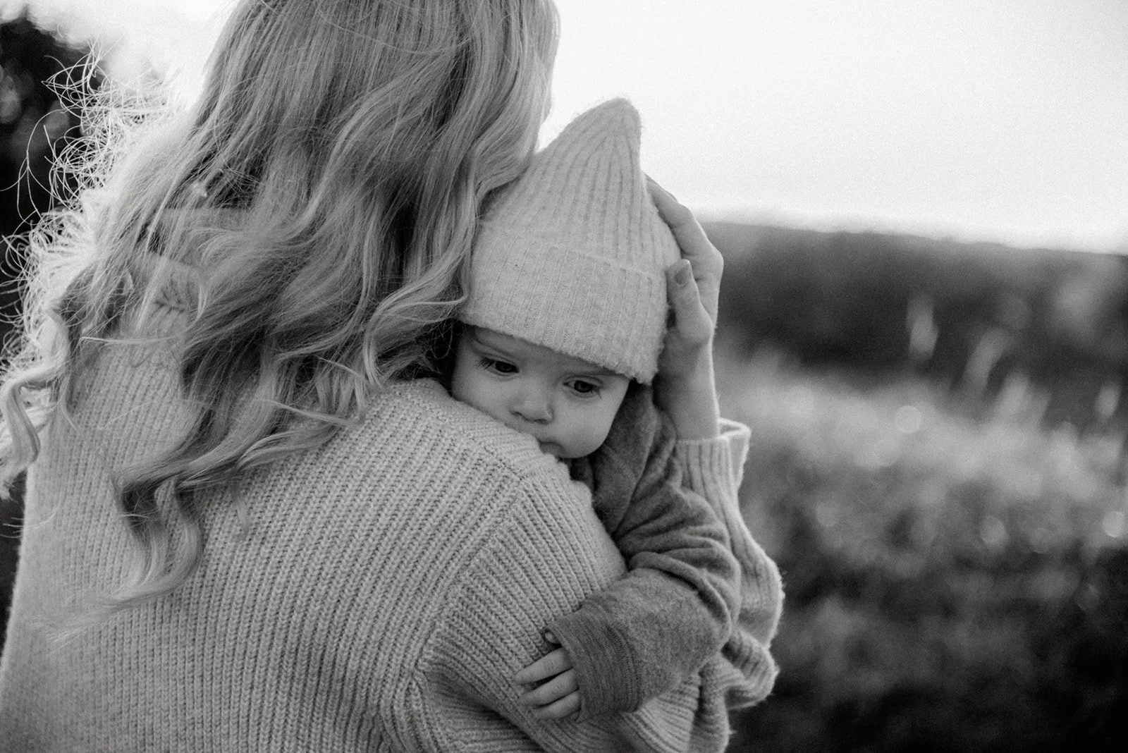 Äiti halaa lasta sylissä mustavalkokuvassa.