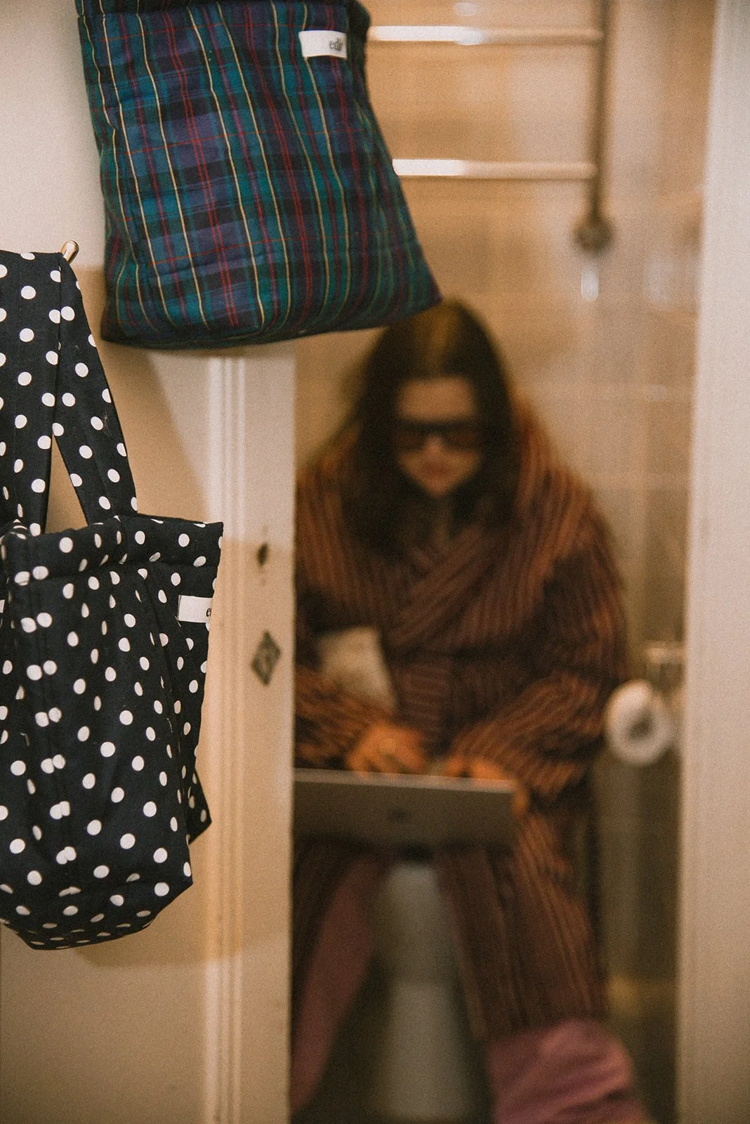 Tuotekuva Edlan laukuista, taustalla yrittäjä kylpyhuoneessa. 