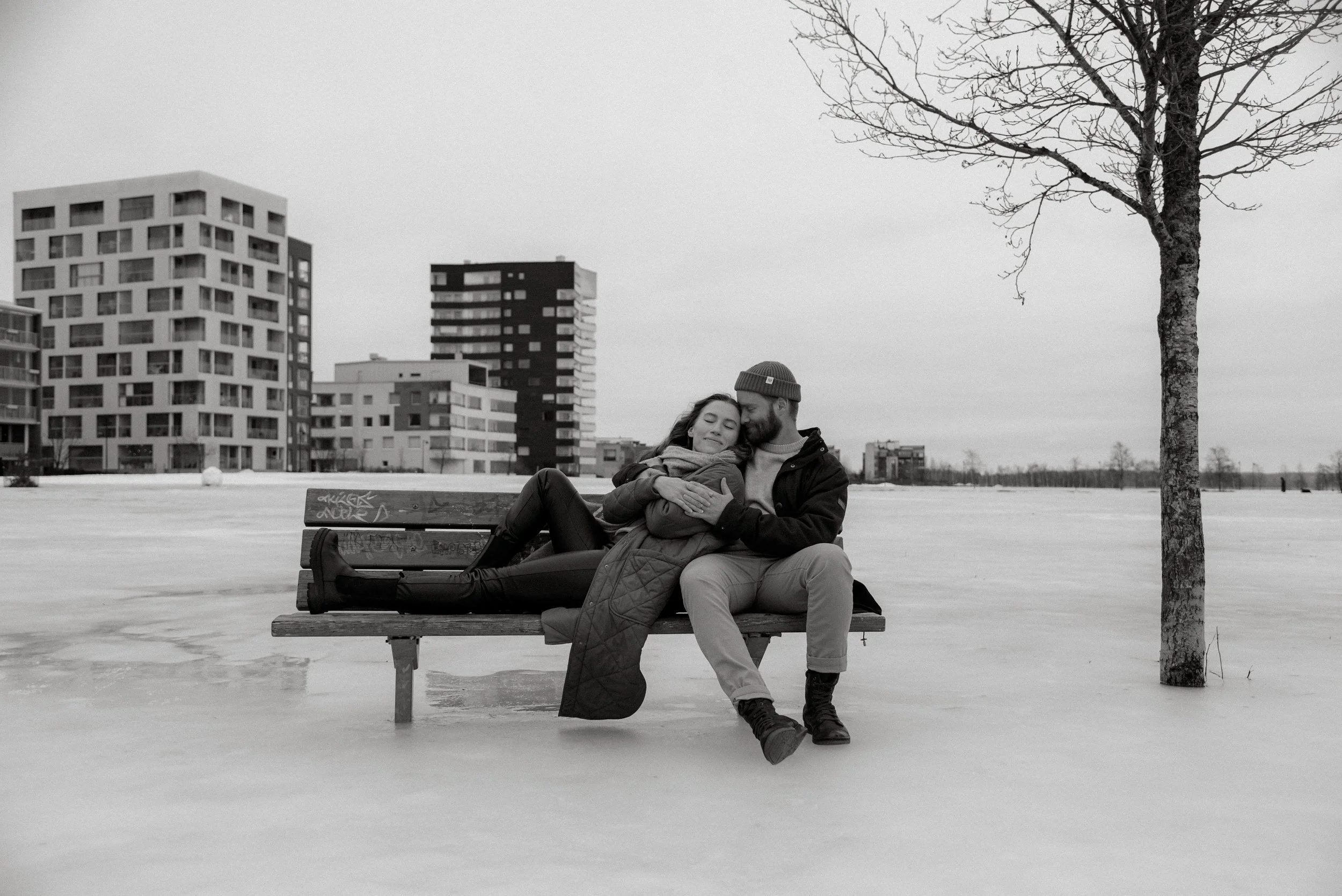 Pariskuntakuvauksessa pariskunta nojautuneena toisiinsa puiston penkillä.