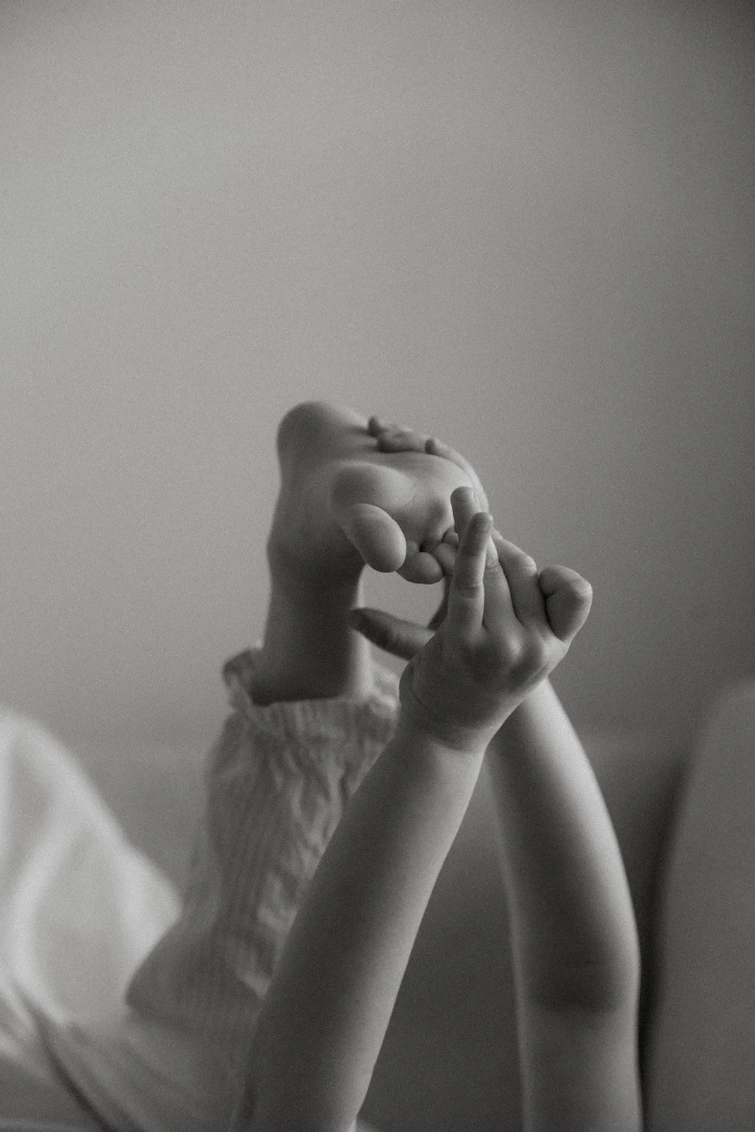 Mustavalkoisessa kuvassa lapsen varpaat ja kädet. Perhekuvaus kotona.