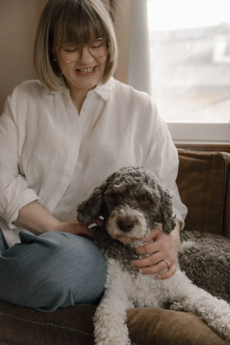 Äiti rapsuttaa perheen koiraa. Perhekuvaus kotona.