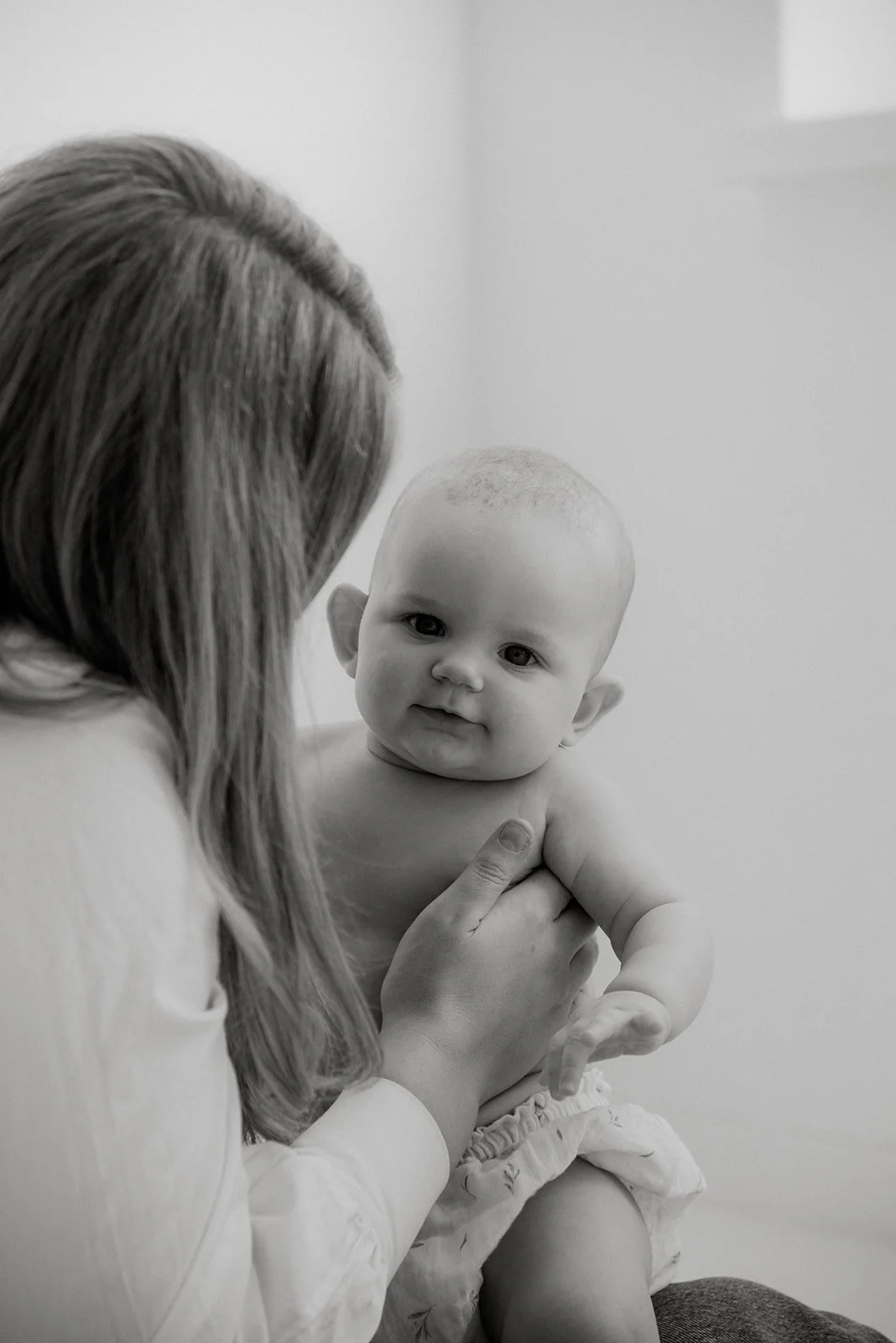 Äiti pitelee lastaan sylissä mustavalkokuvassa. Kuvannut valokuvaaja Heidi Väisänen.