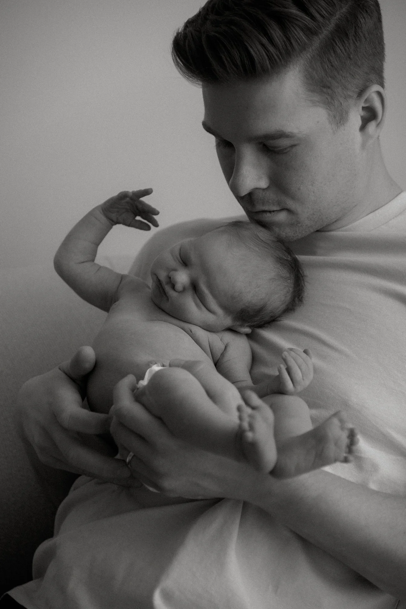 Isä pitelee käsissään vastasyntynyttä vauvaa. Vauvakuvaus Vantaa.