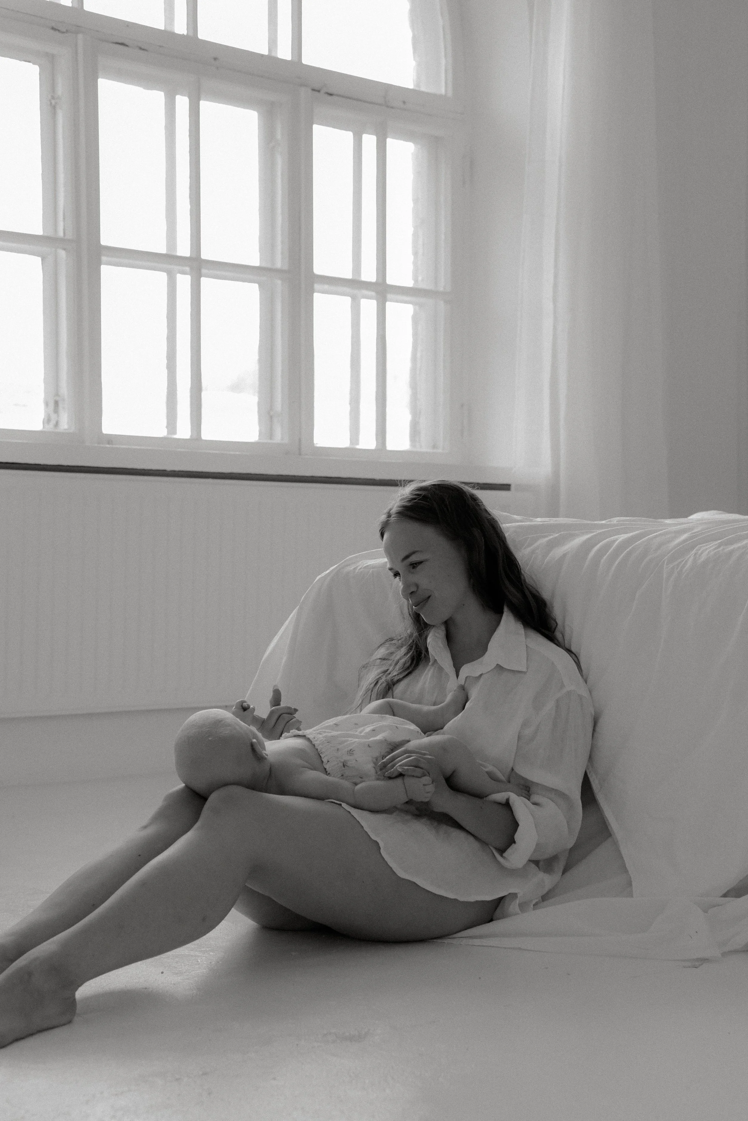 Äiti ja lapsi istuvat valoisan studion lattialla.