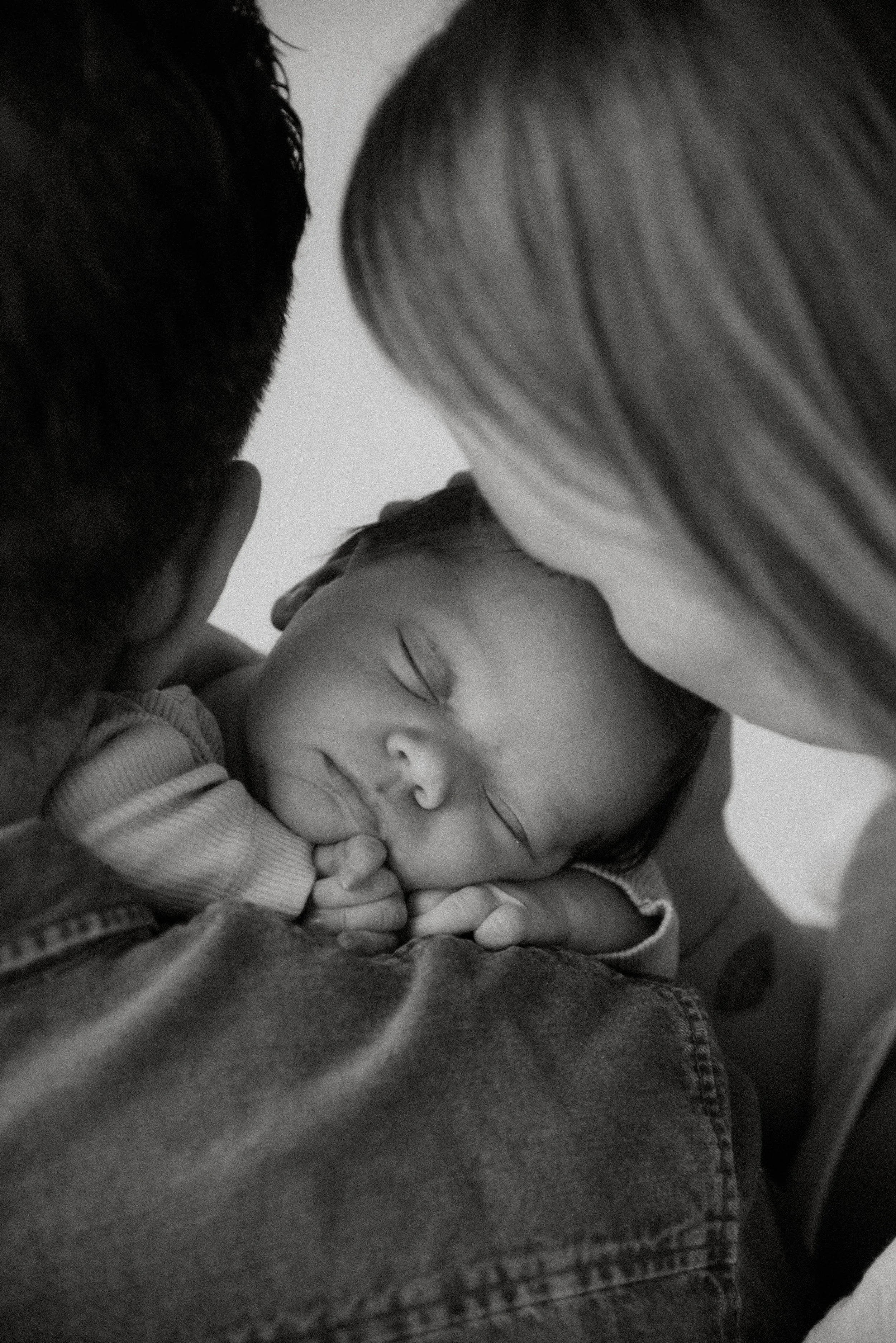 Vastasyntynyt vauva nukkuu isän olkaa vasten.