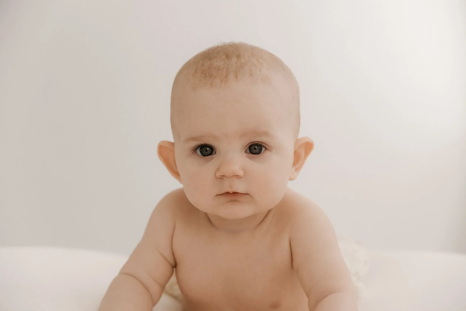 Vastasyntynyt lapsi katsoo suoraa kameraan. Kuvannut vauvakuvaaja Heidi Väisänen.