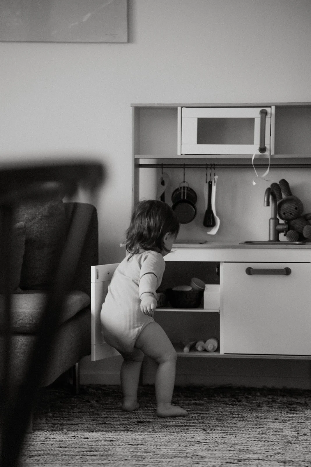 Lapsi leikkii lelukeittiöllä olohuoneessa. Lapsikuvaus kotona.